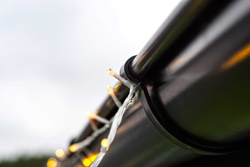 close up of hanging holiday lights safely on a roof to protect it from damage